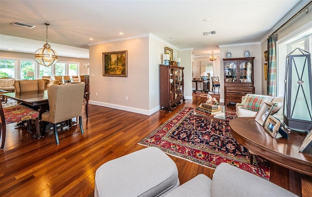 living room featuring dark hardwood / wood-style floors, an inviting chandelier, and ornamental molding