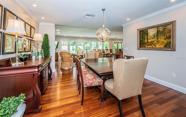 dining space with hardwood / wood-style floors, a chandelier, and ornamental molding