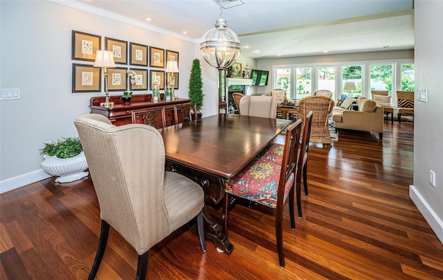 dining area with ornamental molding, an inviting chandelier, and dark hardwood / wood-style flooring