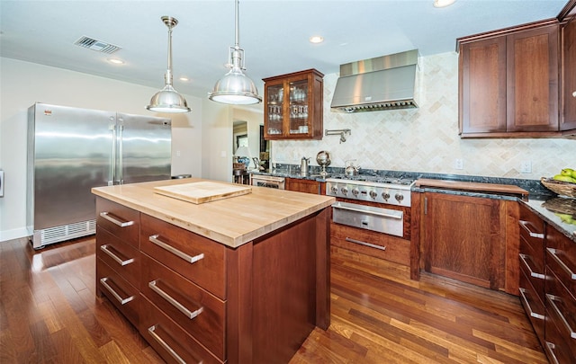 kitchen featuring a kitchen island, dark wood-type flooring, decorative backsplash, wall chimney exhaust hood, and appliances with stainless steel finishes