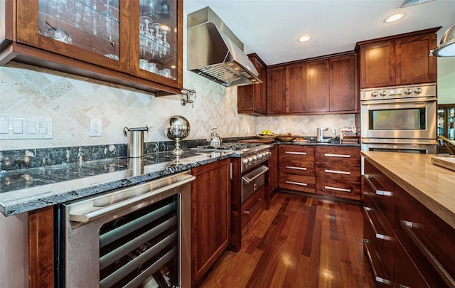 kitchen with dark stone countertops, backsplash, beverage cooler, dark hardwood / wood-style floors, and wall chimney exhaust hood