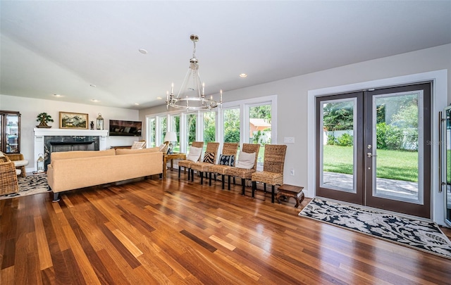 dining area with a high end fireplace, french doors, wood-type flooring, and a chandelier