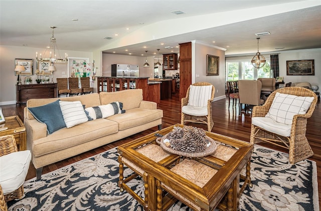 living room with dark hardwood / wood-style flooring, ornamental molding, a chandelier, and vaulted ceiling