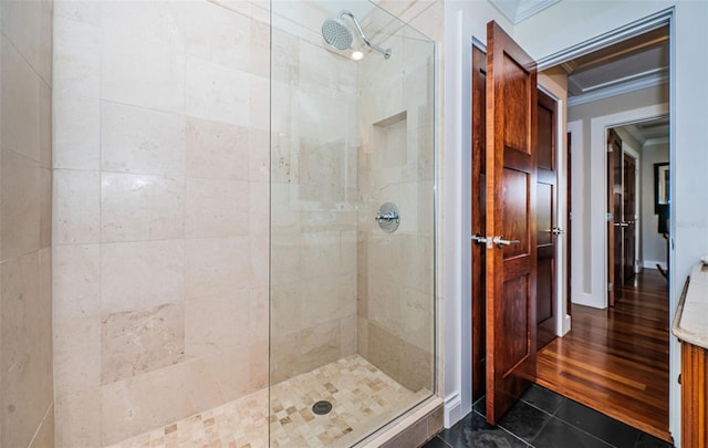 bathroom with ornamental molding, hardwood / wood-style floors, and a shower with shower door