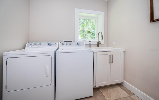 laundry area featuring cabinets, washing machine and clothes dryer, and sink