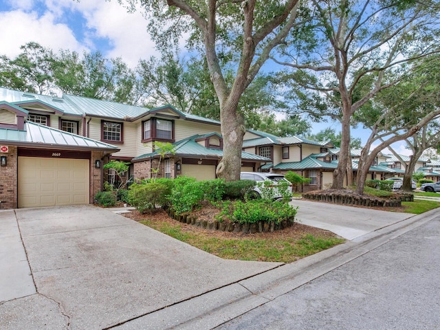 view of property with brick siding, an attached garage, concrete driveway, and metal roof