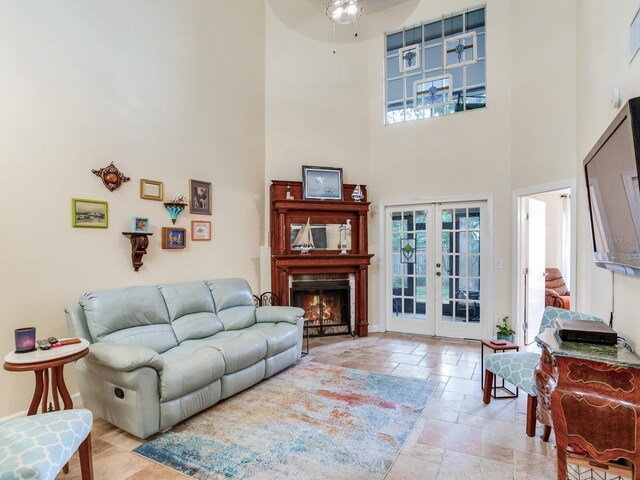 living room with french doors, ceiling fan, and a high ceiling