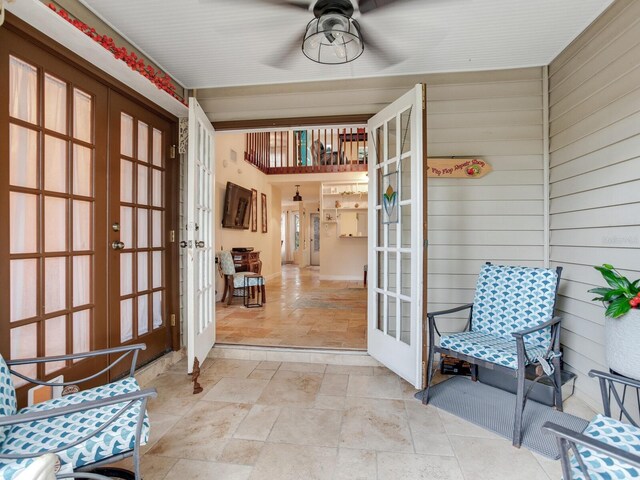 interior space with french doors, ceiling fan, and wooden walls