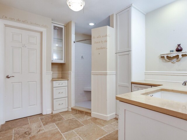 bathroom with tiled shower and vanity