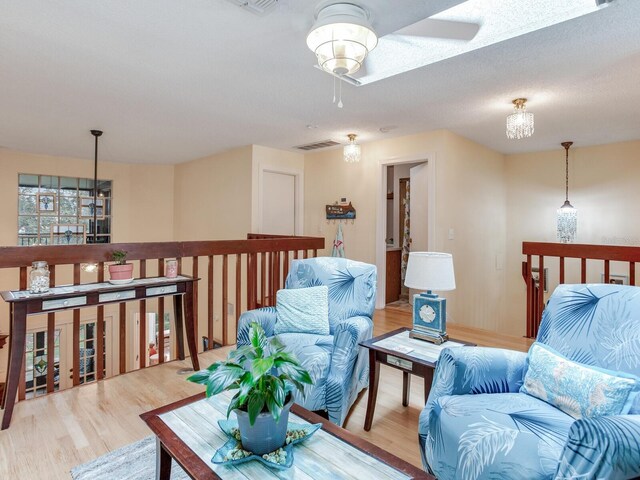 living room with ceiling fan, light hardwood / wood-style floors, and a textured ceiling