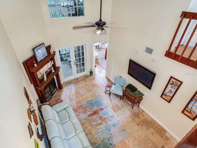 living room featuring ceiling fan, a towering ceiling, and french doors