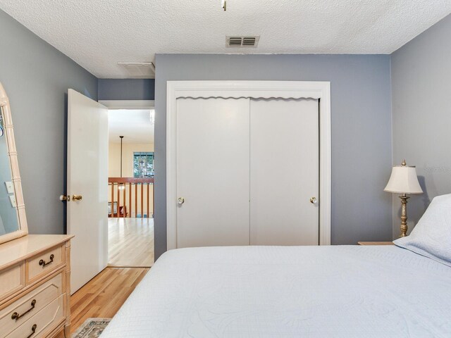 bedroom with a closet, light hardwood / wood-style floors, and a textured ceiling