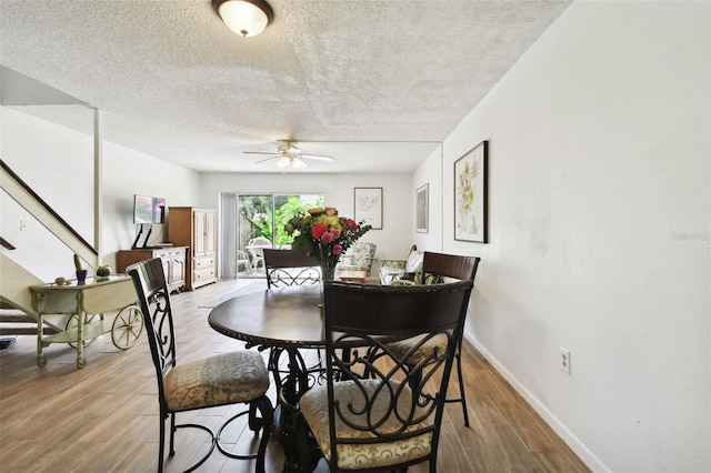 dining space with light hardwood / wood-style flooring, ceiling fan, and a textured ceiling