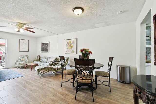 dining area with light wood-type flooring, a textured ceiling, and ceiling fan