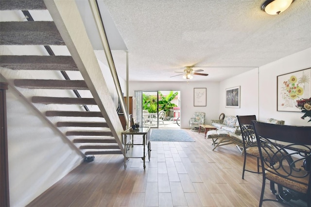 living room with ceiling fan, hardwood / wood-style flooring, and a textured ceiling