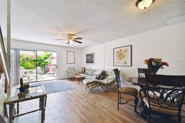 living room featuring ceiling fan, a textured ceiling, and light hardwood / wood-style flooring