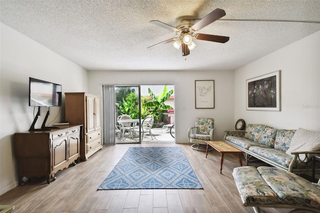 living room featuring ceiling fan, a textured ceiling, and light hardwood / wood-style flooring