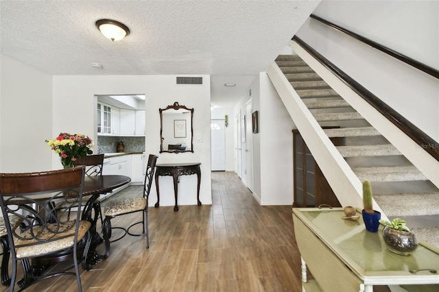 interior space with a textured ceiling and hardwood / wood-style floors