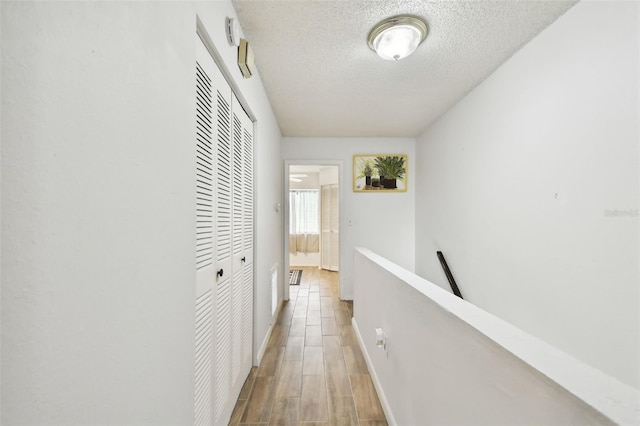 hall featuring a textured ceiling and hardwood / wood-style floors