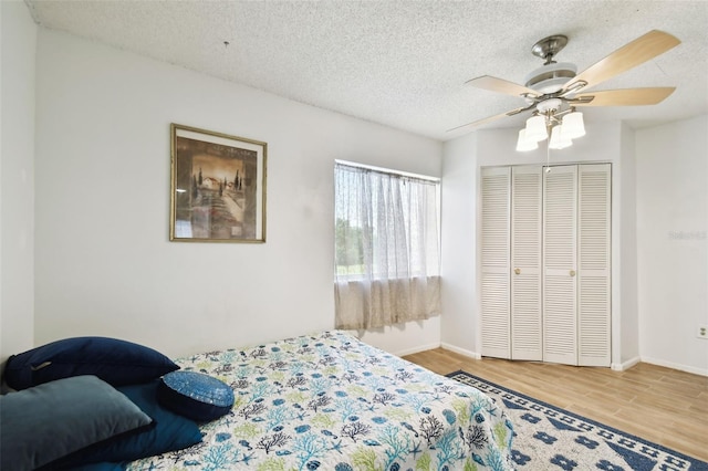 bedroom featuring ceiling fan, a textured ceiling, a closet, and wood-type flooring