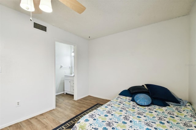 bedroom with ceiling fan, a textured ceiling, ensuite bath, and hardwood / wood-style floors