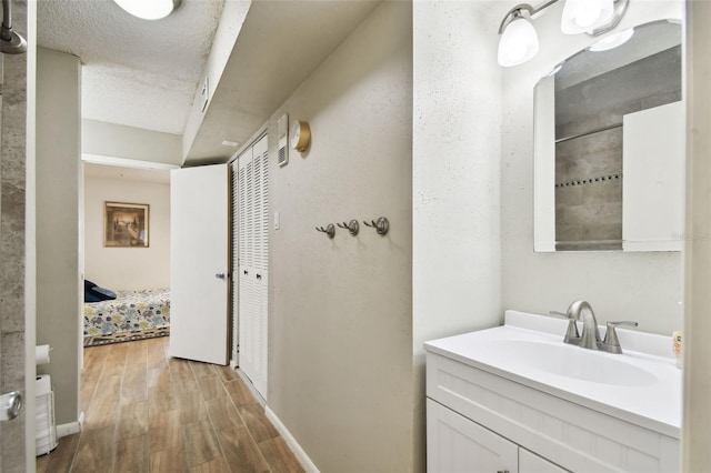 bathroom with a textured ceiling, hardwood / wood-style flooring, and vanity