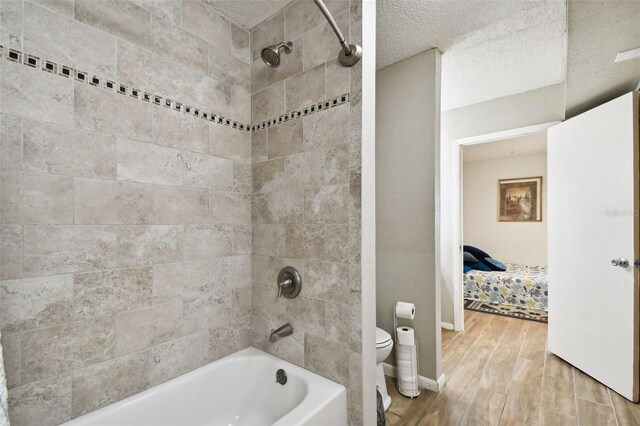 1655 58th Ter S Unit 1, Saint Petersburg, FL 33712 - ensuite bathroom featuring shower / washtub combination, wood finished floors, toilet, and a textured ceiling