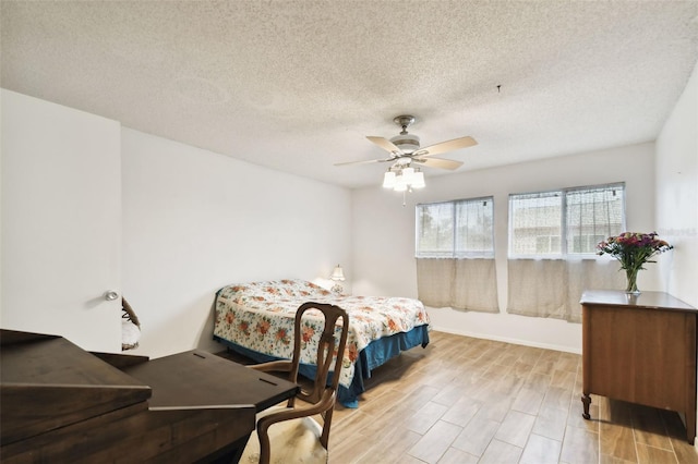 bedroom featuring light wood-type flooring, ceiling fan, and a textured ceiling