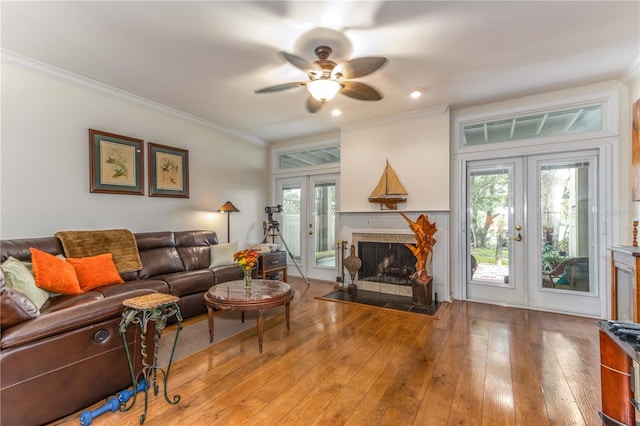 living room with a healthy amount of sunlight, light hardwood / wood-style floors, crown molding, and french doors