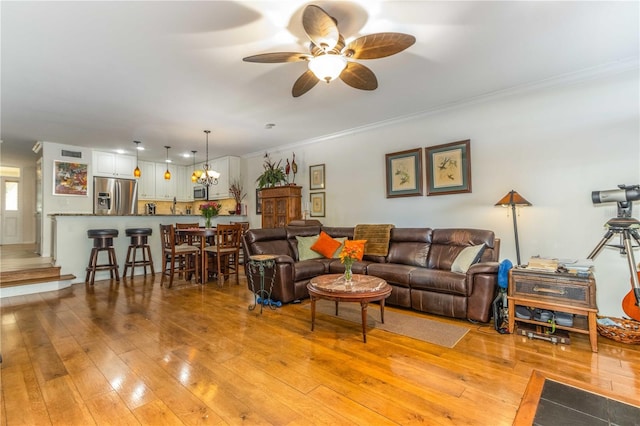 living room featuring ceiling fan with notable chandelier, crown molding, and light hardwood / wood-style flooring