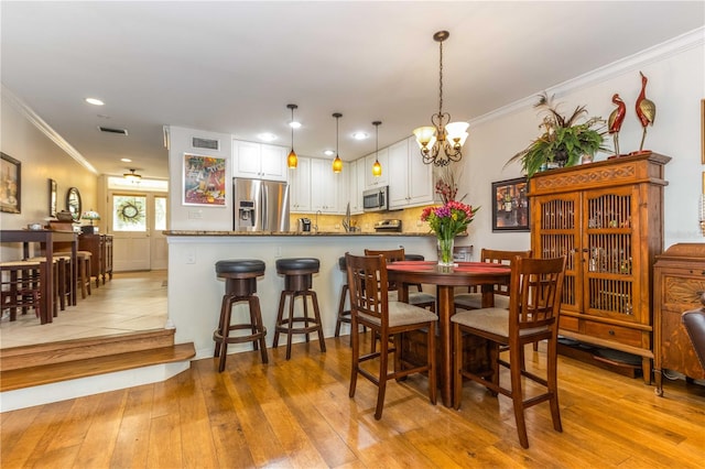 dining area featuring a chandelier, light hardwood / wood-style floors, and ornamental molding