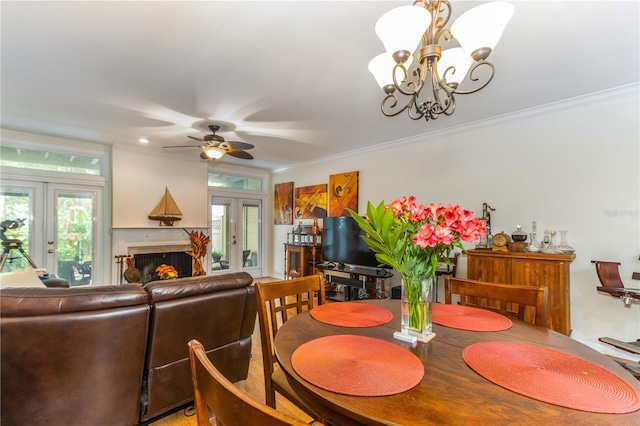 dining area with french doors, ceiling fan with notable chandelier, and ornamental molding