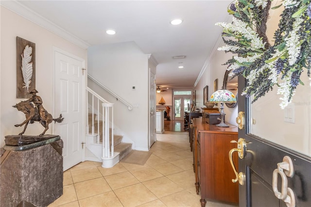 tiled foyer with ceiling fan and crown molding