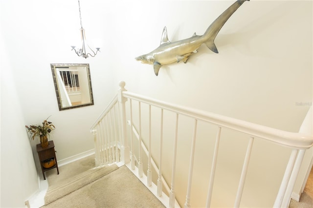 stairway featuring carpet and a chandelier