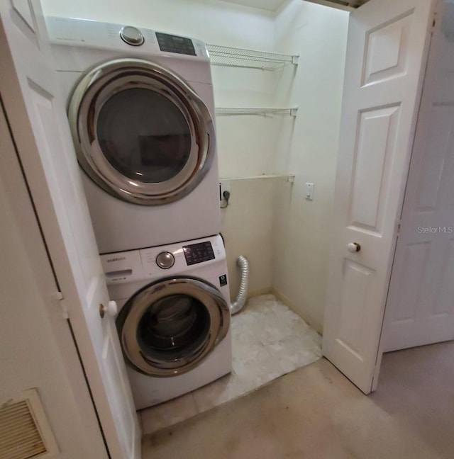 clothes washing area with stacked washing maching and dryer