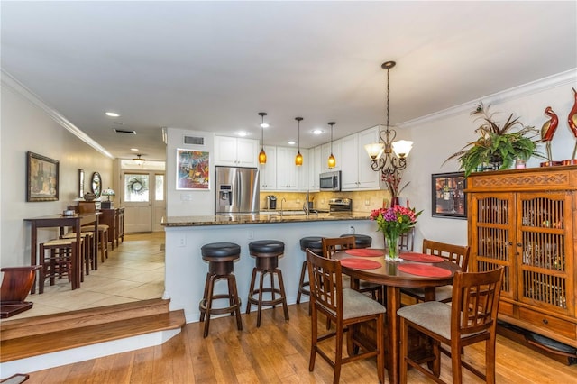 dining space featuring crown molding, a chandelier, and light hardwood / wood-style flooring