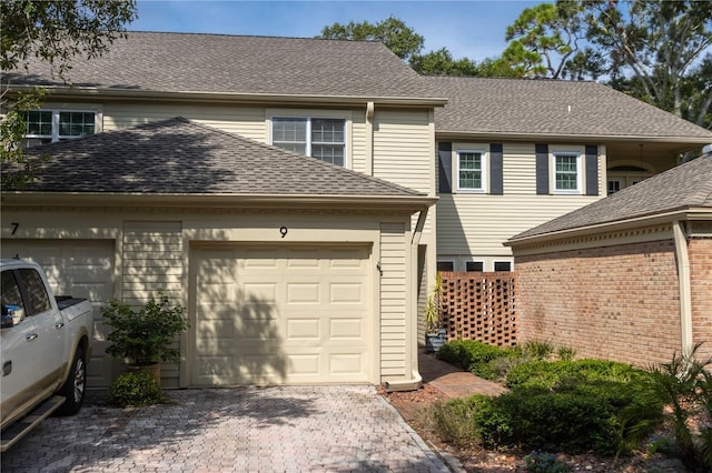 view of front of home with a shingled roof, decorative driveway, and a garage