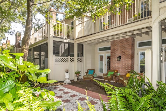 rear view of property with brick siding, a patio area, and french doors