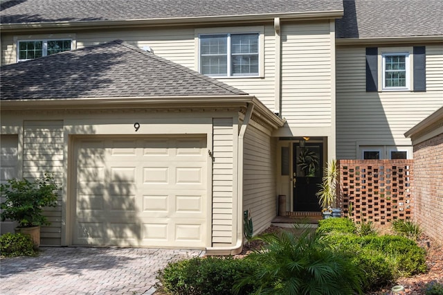 exterior space with an attached garage, driveway, and roof with shingles