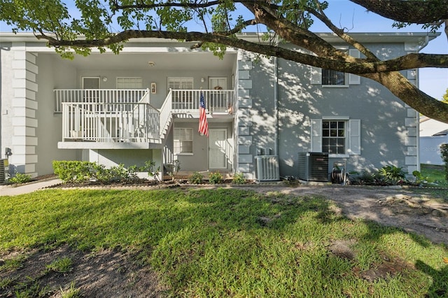 view of front facade with a balcony, central air condition unit, and a front lawn