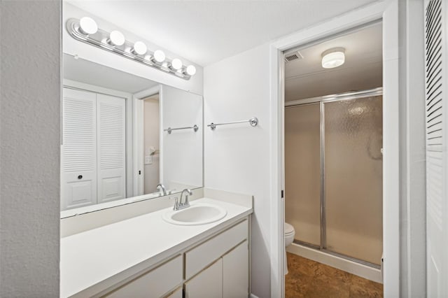 bathroom with vanity, toilet, and a shower with door