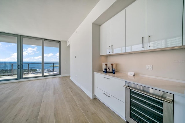 bar featuring expansive windows, white cabinets, wine cooler, light hardwood / wood-style floors, and a water view