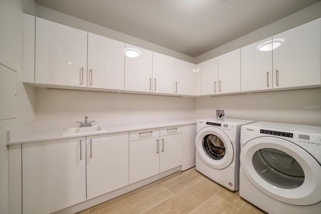 clothes washing area with light hardwood / wood-style flooring, sink, washing machine and clothes dryer, and cabinets