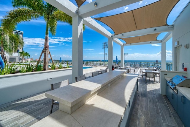 view of patio / terrace with a swimming pool, a water view, and a grill