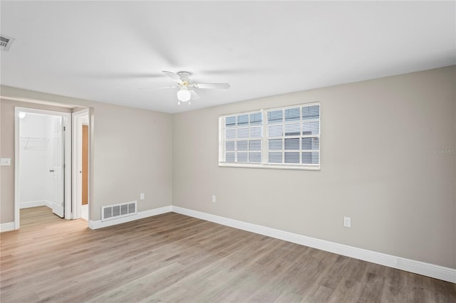 empty room with ceiling fan and light hardwood / wood-style flooring