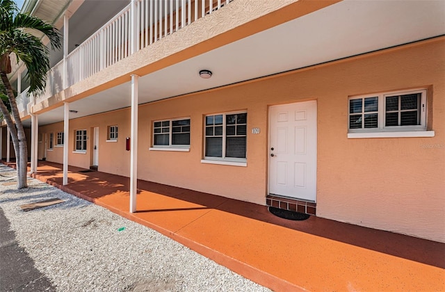 view of exterior entry featuring a patio and a balcony