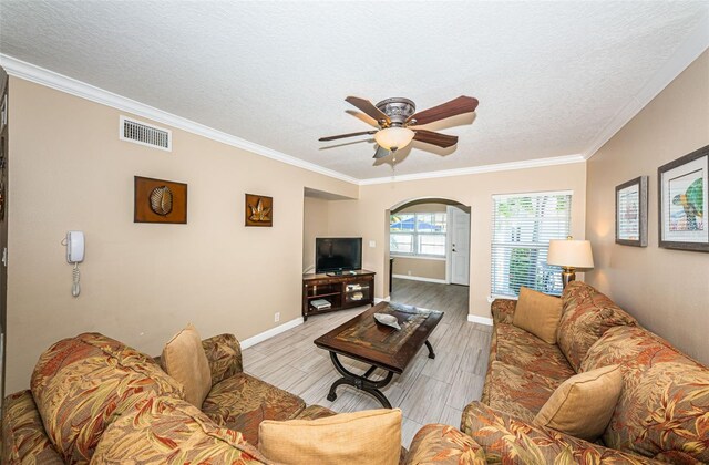 living room with ceiling fan, crown molding, and a textured ceiling