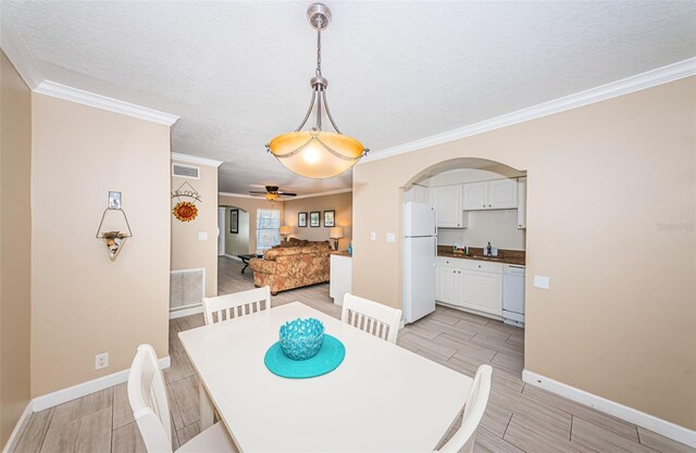 dining area with light wood-type flooring, crown molding, a textured ceiling, and ceiling fan