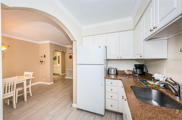 kitchen with sink, white fridge, white cabinetry, dark stone countertops, and light hardwood / wood-style floors