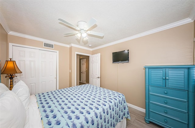 bedroom with light hardwood / wood-style floors, a closet, a textured ceiling, ceiling fan, and ornamental molding